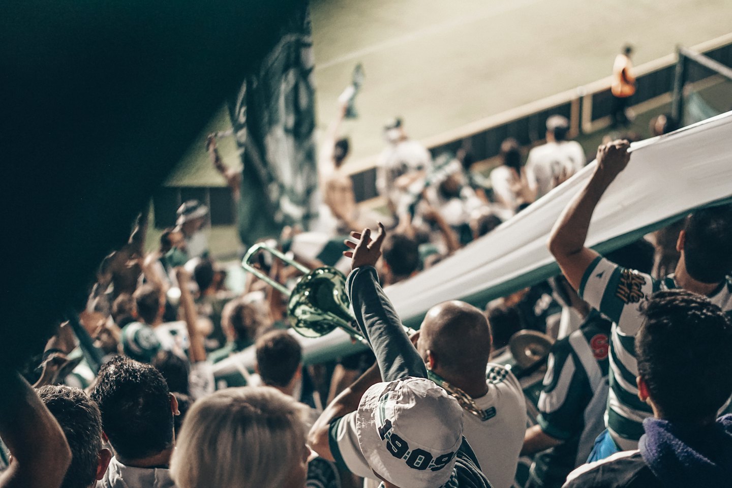 Sports fans in green striped shirts celebrate in a stadium.