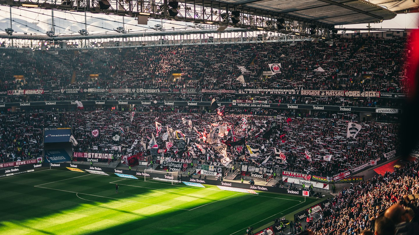 Fans waving flags in a crowded football stadium.